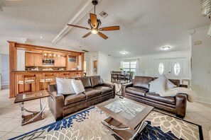 Ein geräumiges Wohnzimmer mit zwei Ledersofas, einem Glastisch und einem Essbereich mit einem Holztisch und Stühlen.