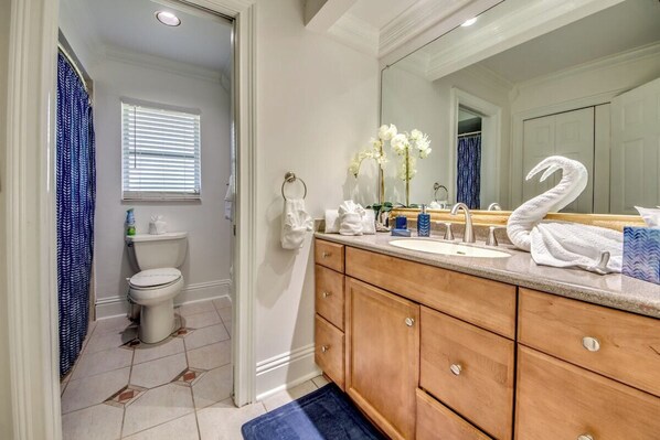 A bathroom with a toilet, sink, vanity, and a large mirror.