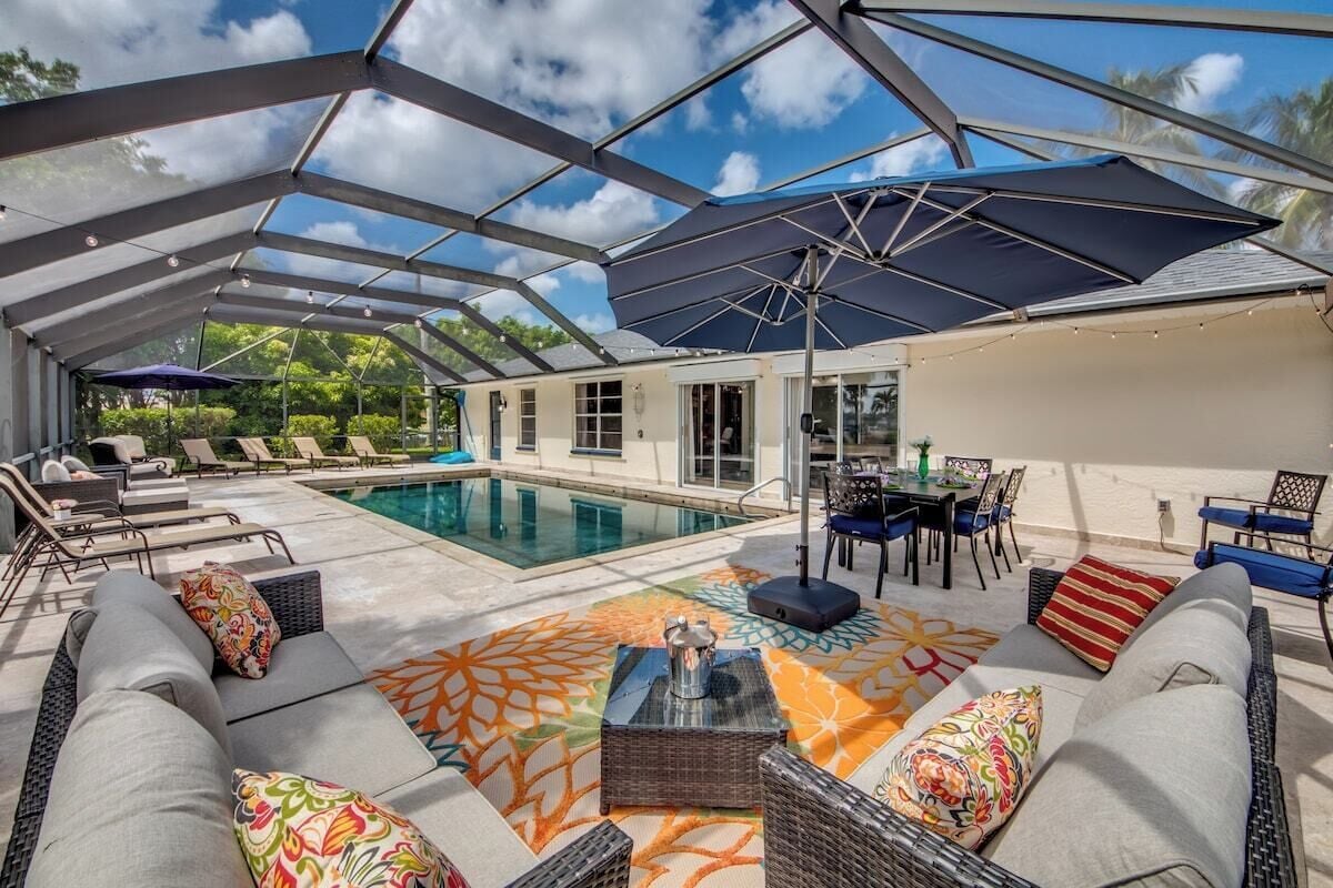 An outdoor pool area with lounge chairs, a dining table, and umbrellas.