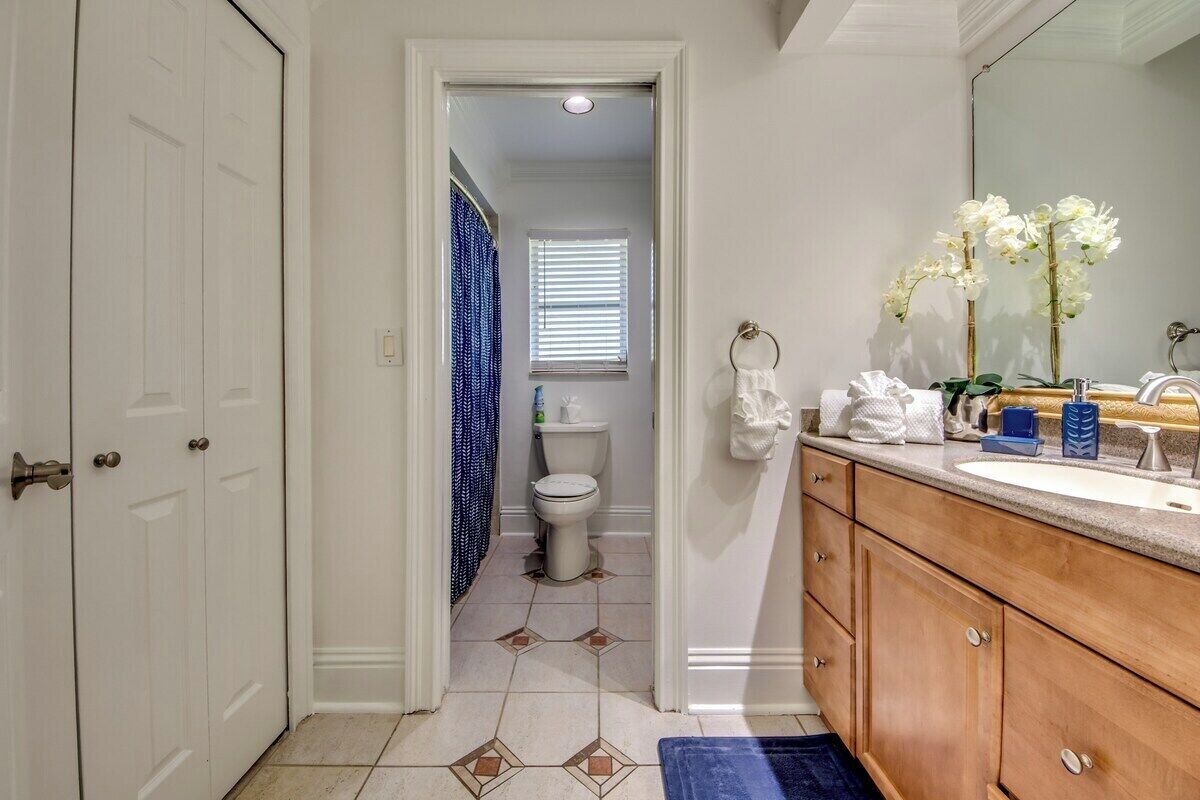 Een badkamer met een witte deur, een toilet, een wastafel met spiegel en een blauwe badmat.