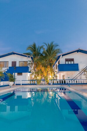 Una piscina al aire libre, sombrillas, sillones reclinables de piscina