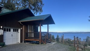Une cabane en bois avec un porche couvert, un garage et une allée gravillonnée.
