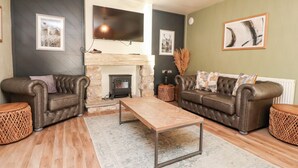 Una sala de estar moderna con dos sofás de cuero, una mesa de centro de madera y una chimenea de piedra.