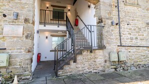 A stone building with a staircase leading to a second floor. There is a sign on the wall indicating the building's name and location. - Eldroth (Skipton)