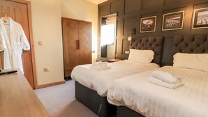 Habitación de hotel con dos camas, un armario de madera, un escritorio con un control remoto y un espejo.