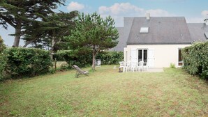 A house with a white exterior, a grey roof, and a small patio area with white chairs and a table. - LES AJONCS - 300m de la plage - Parking (Batz-sur-Mer)