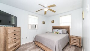 A bedroom with a bed, nightstands, a dresser, a ceiling fan, and a TV. - Fabulous Views, Updated, Minutes to ICW & Beach (Bay City)
