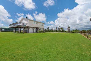 A two-story house with a balcony, surrounded by a well-maintained lawn and palm trees.