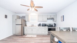 A modern kitchen with white cabinets, stainless steel appliances, and a wooden dining table. - Fabulous Views, Updated, Minutes to ICW & Beach (Bay City)