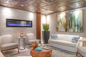 Uma sala de estar moderna com lareira, área de estar e arte abstrata nas paredes.