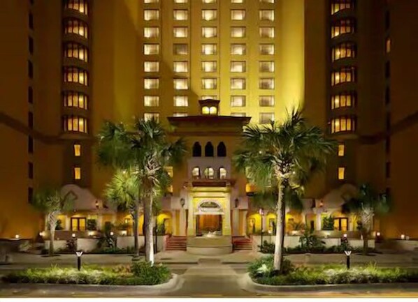 Stunning hotel entrance with a central balcony and beautifully landscaped surroundings.