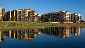 Een hotel met meerdere verdiepingen, een reflectie in het water, en een heldere lucht.