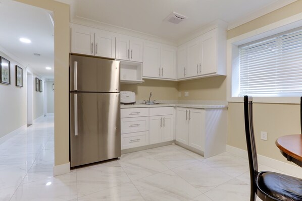A modern kitchen with white cabinets, a stainless steel refrigerator, a built-in oven, and a window with blinds. - Superb Convenient North Delta Vacation Home with 6 Bed and 6 Bath (Delta)
