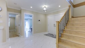 A spacious room with a wooden staircase, a white door, and a light-colored floor. - Superb Convenient North Delta Vacation Home with 6 Bed and 6 Bath (Delta)