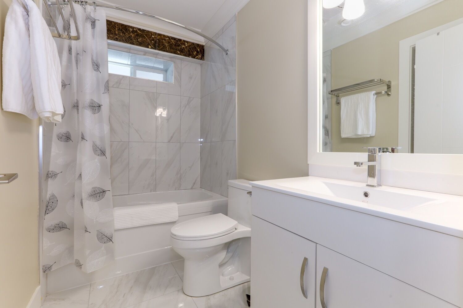 A modern bathroom with a shower, toilet, and vanity.