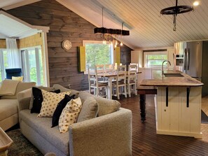 A cozy living area with a sofa, dining table, and kitchen with a built-in island. - Rustic Meets Luxury (Lanark)