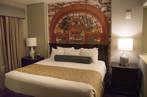 Relax in a serene space with a large bed, decorative arch, and views of a tranquil fountain and palm trees.