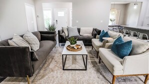 A modern living room with a dark brown sofa, a white sofa, and a beige sofa, all arranged around a central coffee table. - NEW! Pinehurst Eight Sleeps 10! (Pine Hurst)