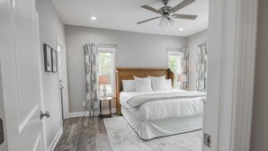 A bedroom with a wooden headboard, a ceiling fan, and a large bed with white bedding. - NEW! Pinehurst Eight Sleeps 10! (Pine Hurst)