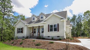 A two-story house with a front porch, a covered entryway, and a landscaped front yard. - NEW! Pinehurst Eight Sleeps 10! (Pine Hurst)