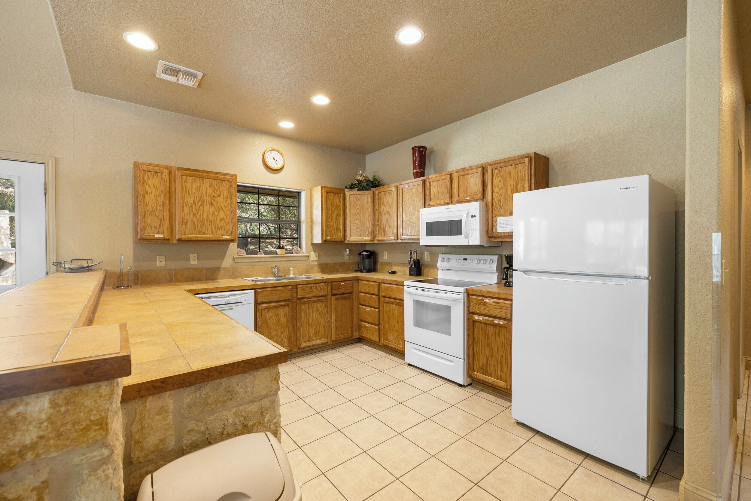 A kitchen with wooden cabinets, a white refrigerator, a microwave, and a stove.