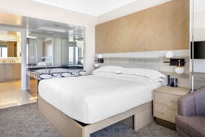 Une chambre à coucher moderne avec un grand lit, une tête de lit en bois, des tables de chevet et un miroir.