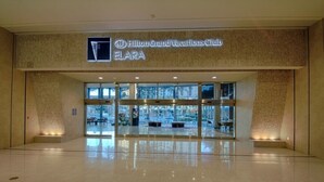 The entrance to the Hilton Grand Vacations Club FLARA with a modern glass facade and a sign above the entrance. - Las Vegas | Pool & Strip Access | City Escape Stay (Las Vegas)
