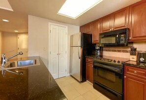 Enjoy cooking in this well-equipped kitchen with a stainless steel sink, double-door refrigerator, microwave, and gas stove.