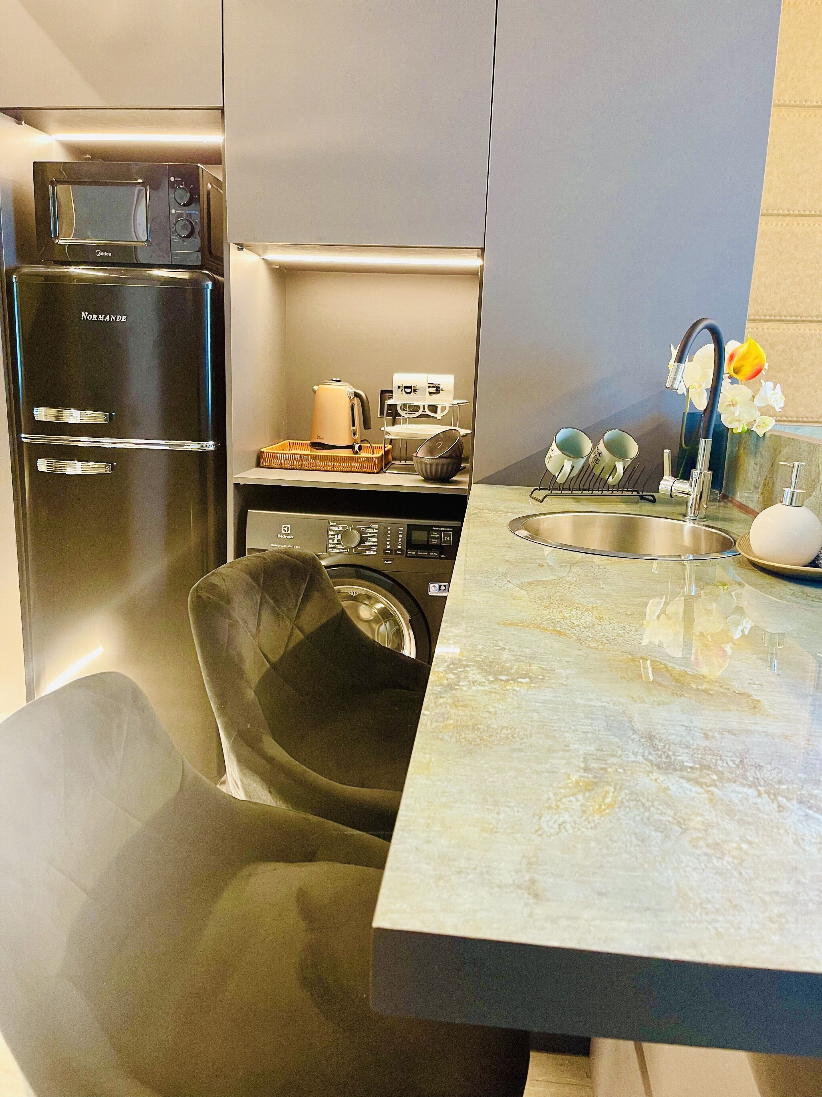 Une cuisine compacte équipée d’un lave-linge, d’un four à micro-ondes et d’un évier.