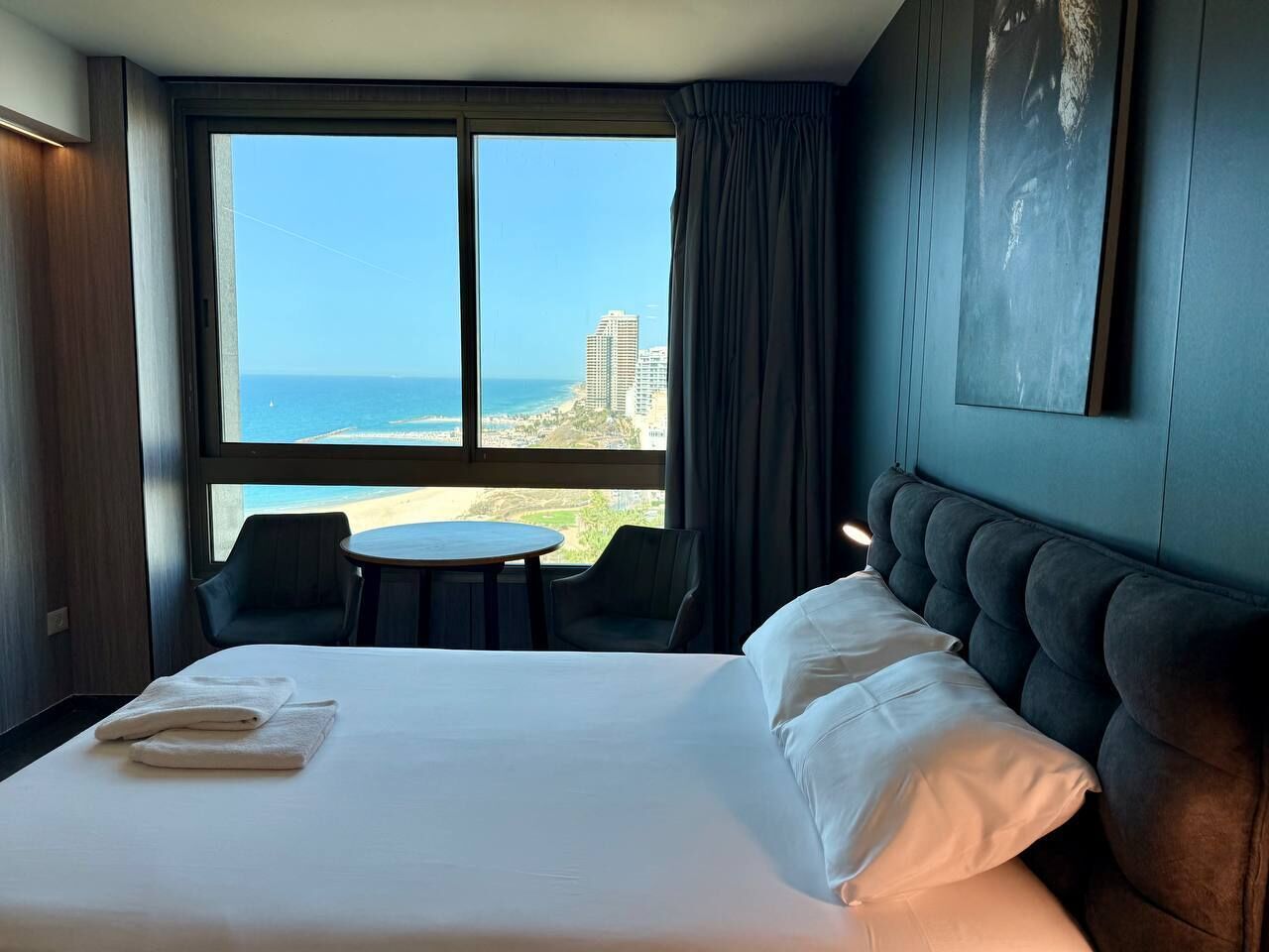 Habitació d'hotel amb un llit gran, vistes a l'oceà i zona menjador amb dues cadires.
