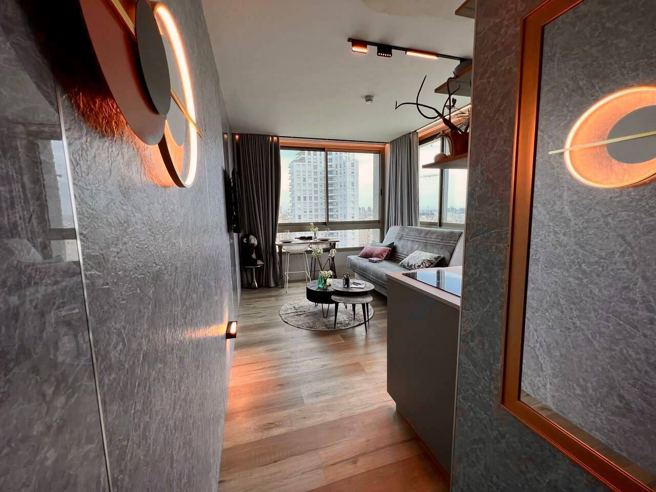 Un salon moderne avec un canapé, une table basse et une vue sur la ville grâce à de grandes fenêtres.