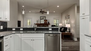 A modern kitchen with white cabinets, a black and white backsplash, stainless steel appliances, pendant lighting, and a ceiling fan. - Serenity on Pinehurst No 6! <3.5 miles to the Village of Pinehurst! Sleeps 10! (Pine Hurst)