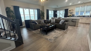 A spacious living room with a large window, a ceiling fan, and a view of the water. - SUNSET RETREAT-Luxury 4BR, 4.5BA waterfront, boat lift, best sunset on the lake! (Russells Point)