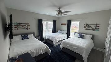 Une chambre avec deux lits, un ventilateur de plafond et des fenêtres avec des rideaux.