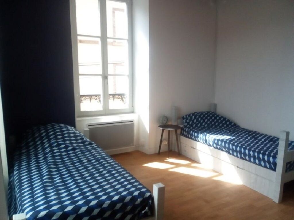 Een kleine, lichte kamer met twee eenpersoonsbedden, een raam en een radiator.