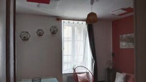 A room with a dining table, a red chair, a sofa, and a window with curtains. - Pounette, T3 apartment center / Luxeuil thermal baths (Luxeuil-les-Bains)