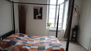 A room with a bed, a window, a plant, and a painting on the wall. - Pounette, T3 apartment center / Luxeuil thermal baths (Luxeuil-les-Bains)