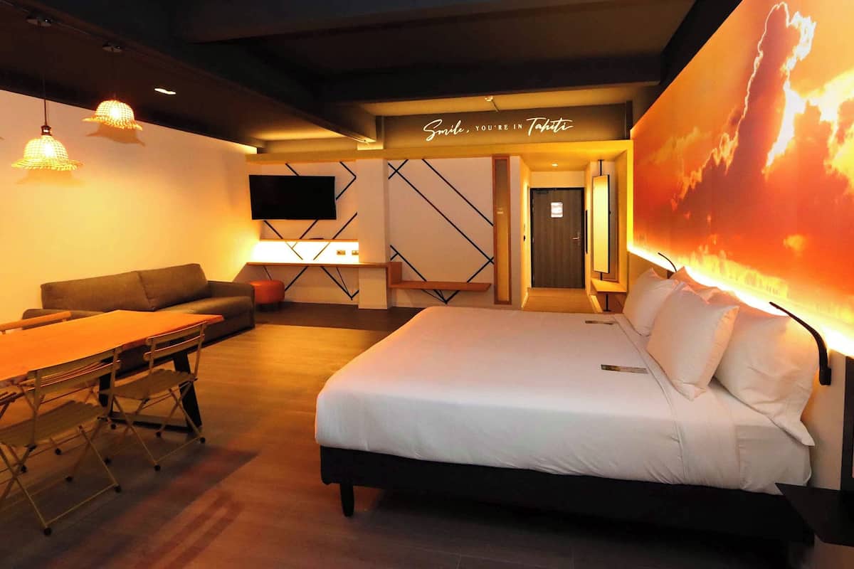 Een moderne hotelkamer met een bed, een slaapbank, een bureau en een televisie.