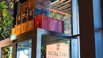 A display of stacked suitcases on a shelf above a sign for the Kontiki Boutique Hotel.