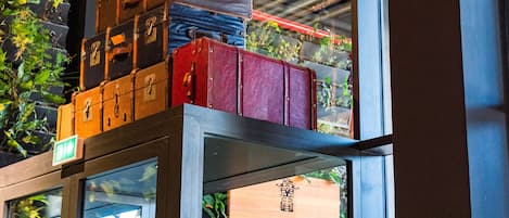 Gestapelde koffers op een plank boven een bord met daarop Kontiki Boutique Hotel.