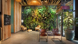 Een modern interieur met een verticale tuin, rieten meubels en een grote potplant.