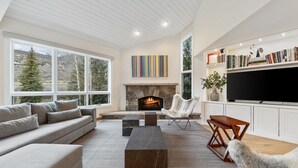 A modern living room with a fireplace, large windows, and a television.
