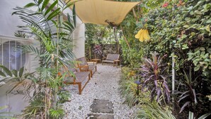 Ein Garten mit einem Pfad, Holzmöbeln und unterschiedlichen Pflanzen.