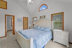 A bedroom with a bed, dresser, and a ceiling fan.