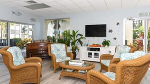 A room with wicker furniture, a flat-screen TV, and a view of the outdoors. - Condo# 107  Two minutes walk to the Beach! (Sarasota)