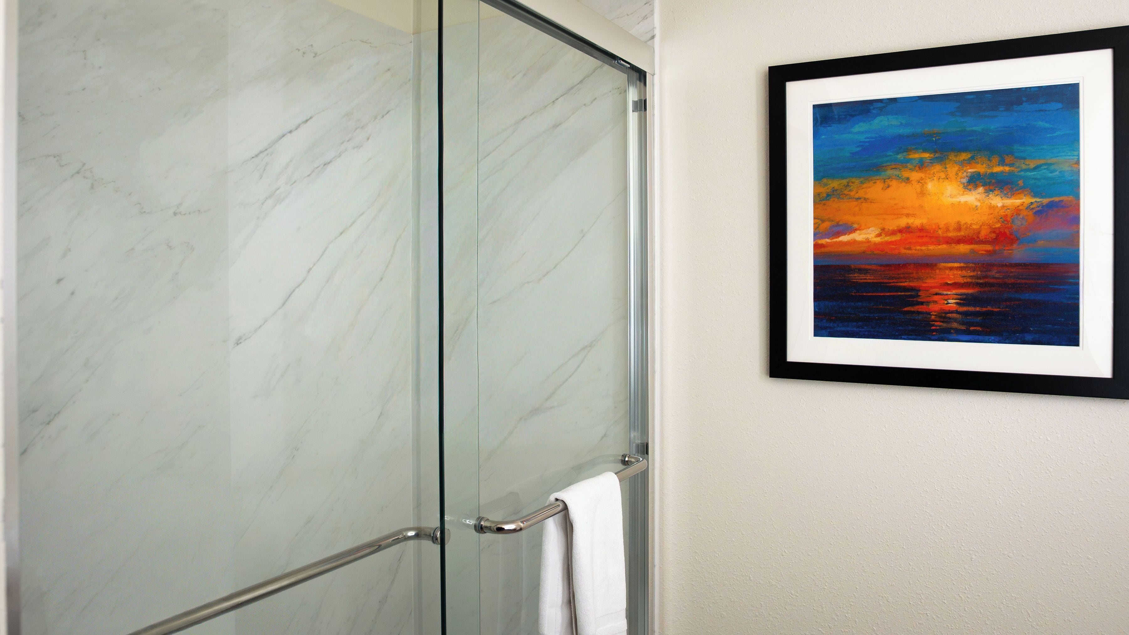 A glass shower enclosure with a white towel on the door handle.