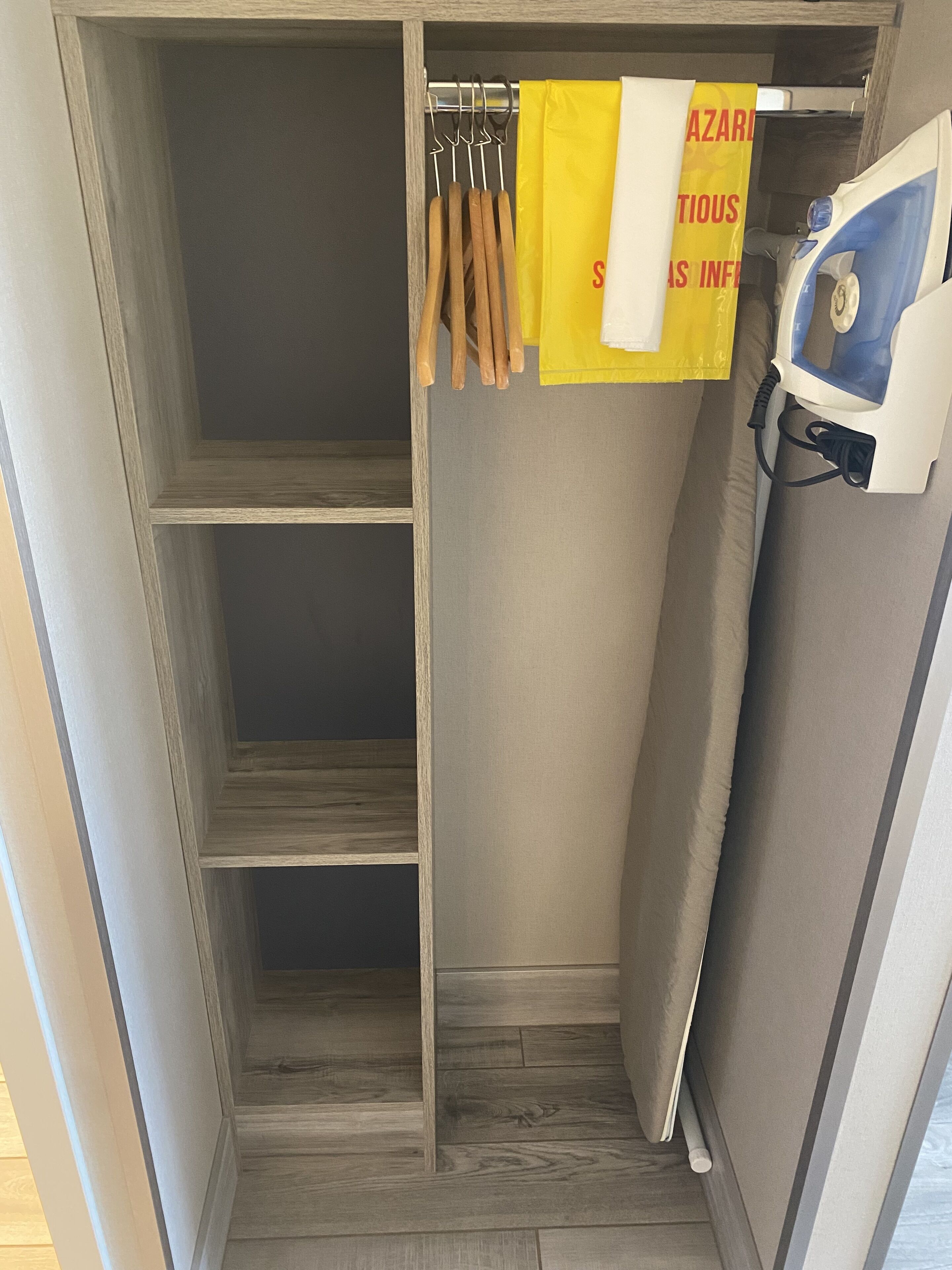 Un dressing avec des étagères en bois, une tringle à vêtements et un fer à repasser à vapeur.