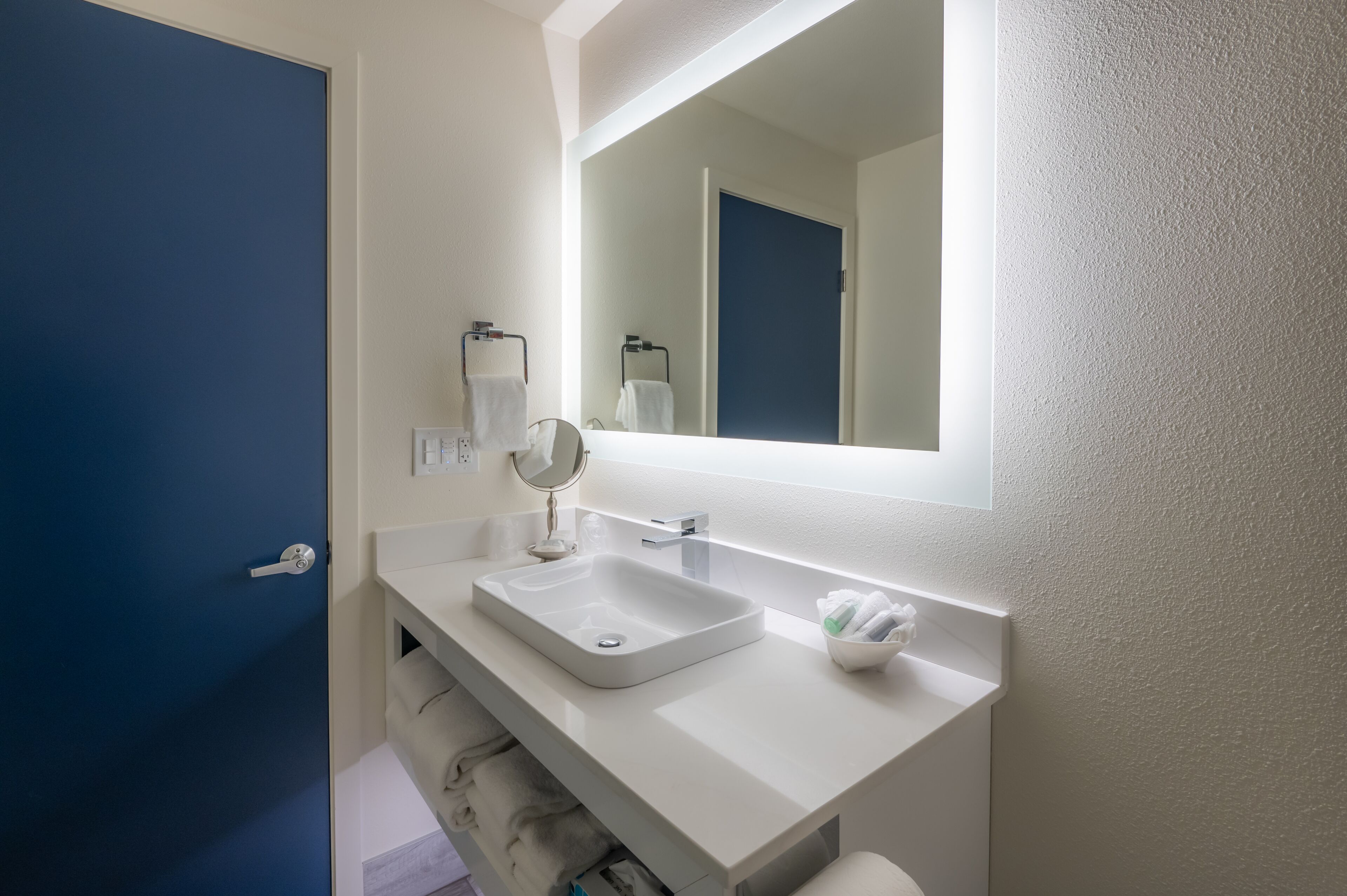 A bathroom with a white sink, a mirror, and a towel rack.