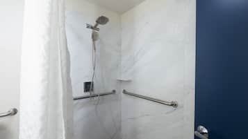 A bathroom with a shower, marble walls, and a blue door.