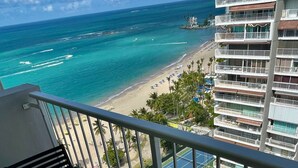 A balcony with a table and chairs overlooking a beach and ocean. - Luxurious Ocean View Studio Next to Major Hotels (Carolina)